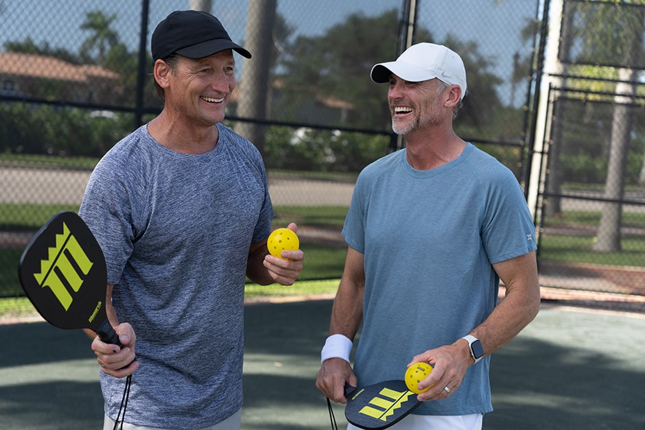 two men on pickleball court with balls and racquets